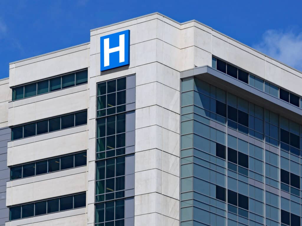 Large modern building with blue letter H sign for hospital.