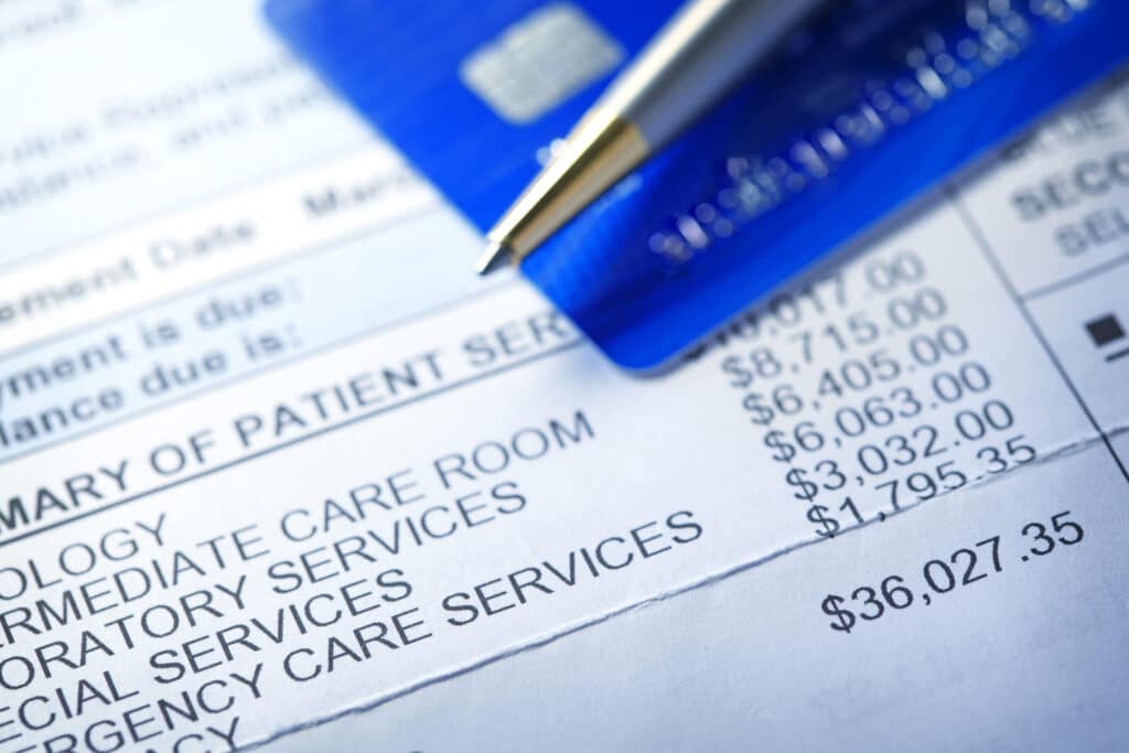 credit card and pen resting on an itemized hospital invoice