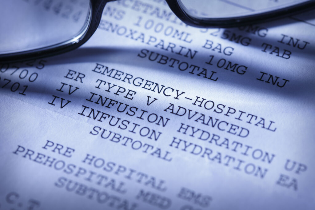 A close up of a hospital bill with glasses laid on top of the paper.