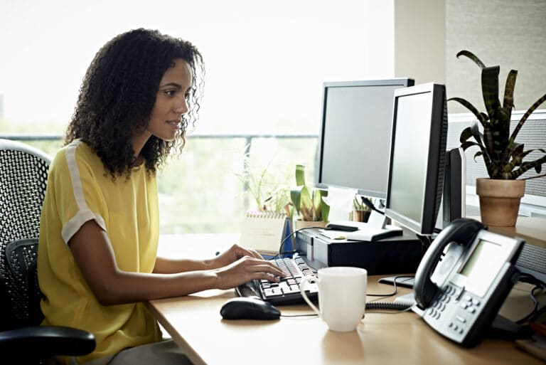 business woman sitting at a desk in an office setting using a computer provider revenue integrity, payer revenue integrity, payment integrity, revenue integrity