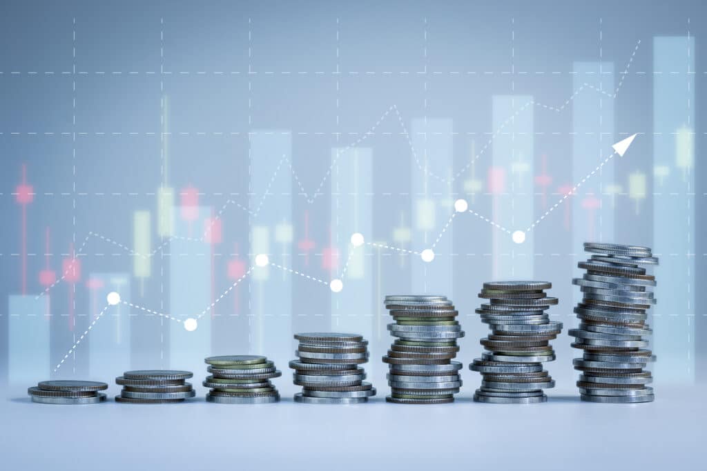 Coins stacked in front of an upward trending graph.