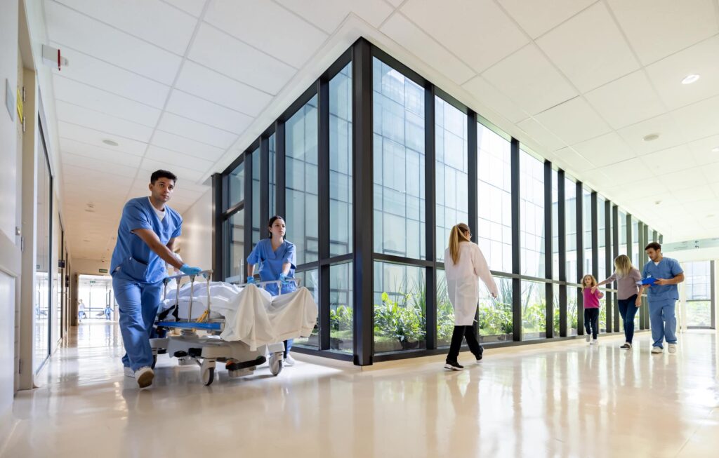 doctors wheeling a patient in a bed down a hallway at a hospital provider revenue integrity, payer revenue integrity, payment integrity, revenue integrity