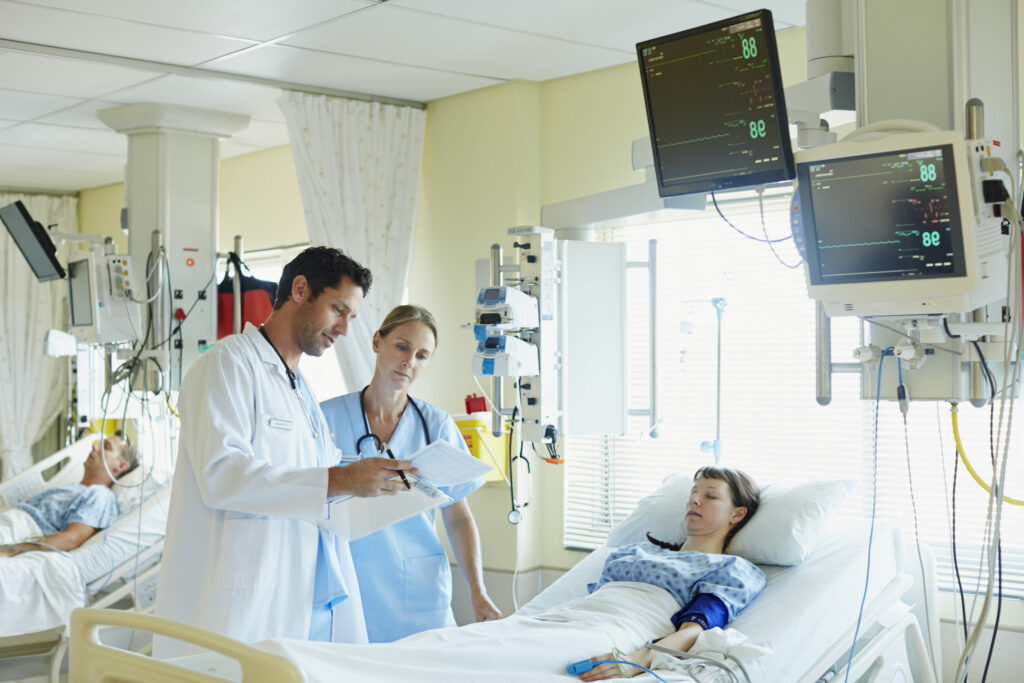doctor and nurse examining reports of patient lying in icu